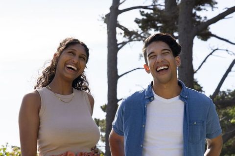 Young african american couple laughing together outdoors on sunny coastal park day