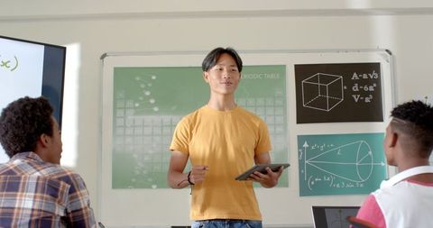 Educator Holding Tablet Presenting to Students in Classroom