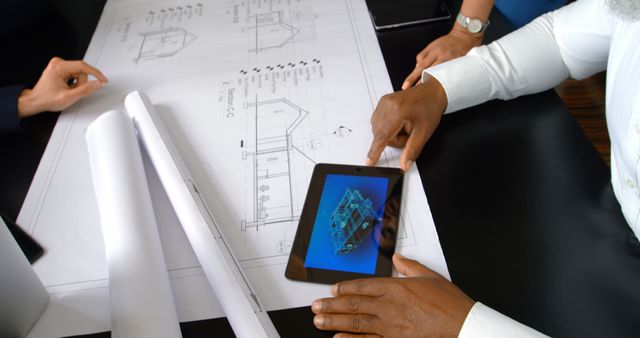 Professionals review architectural plans on a tablet in an office. Collaboration is key in this setting, where expertise meets technology.