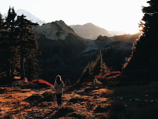 Woman enjoying breathtaking mountain scenery during sunset, perfect for themes of adventure, natural beauty, and solitude. Ideal for travel blogs, outdoor gear advertisements, nature conservation campaigns, and inspirational social media posts.