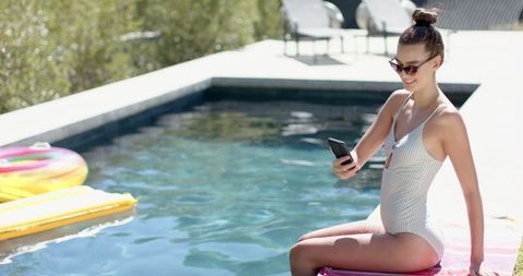 Teen Girl Using Smartphone by Pool on Sunny Day