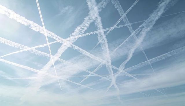 Crisscrossing contrails forming geometric grid over clear blue sky