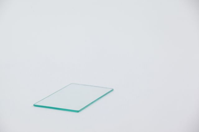 This image shows a close-up of a single sheet of glass placed on a white background. The simplicity and clarity of the image make it ideal for use in design projects, presentations, and advertisements related to construction, architecture, or modern design. It can also be used to represent concepts of transparency, minimalism, and simplicity.