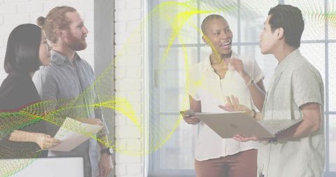 Diverse team collaborating around laptop and documents in bright modern office workspace