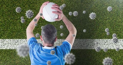 Athlete Holding Ball Overhead with Virus Molecules on Turf