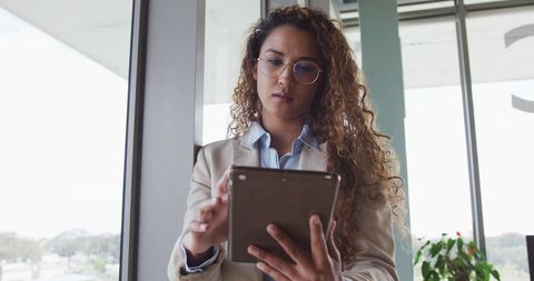Businesswoman in Office Using Tablet Near Large Window