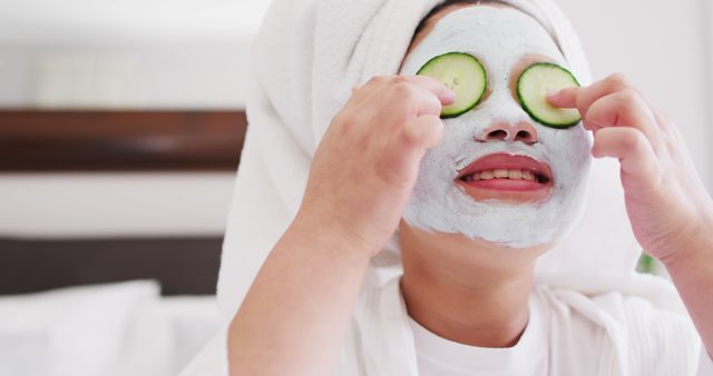 Image of happy asian girl in robe doing cucumber mask and having fun. Family, motherhood, relations and spending quality time together concept digitally generated image.