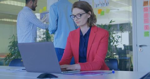 Female Professional Typing in Modern Office with Colleagues Collaborating