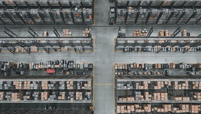 Aerial view showing high-density warehouse aisles with pallet racks, boxes, logistics flow