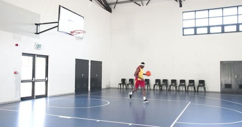 Athlete dribbling ball on indoor basketball court