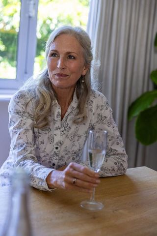 Elegant Senior Woman Enjoying Glass of Champagne in Sunlit Room