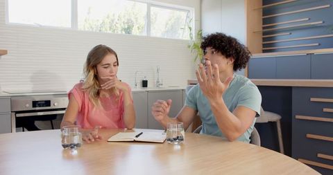 Young Couple Collaborating at Kitchen Table With Notebook
