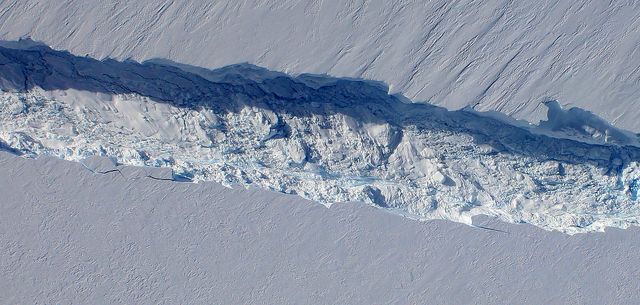 This aerial image captures a detailed view of a crack spreading across Pine Island Glacier's ice shelf. The image reveals the intricate structure of the ice blocks that fell into the rift. This crack, photographed by NASA's Digital Mapping System (DMS) on October 26, 2011, stretches approximately 240 feet wide and ranges from 165 to 190 feet deep. It highlights the ongoing changes in Antarctic ice, with scientists predicting the crack will result in a 300-square-mile iceberg calving. Suitable for climate change documentation, geological studies, and educational material on glaciology.