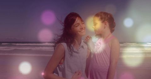 Mother and daughter smiling on beach at sunset with bokeh lights, family bonding portrait