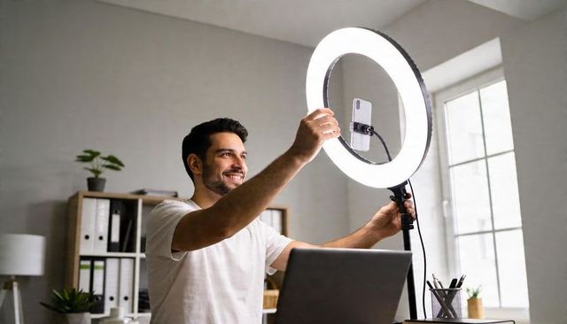 Content creator adjusting ring light and smartphone while recording in bright home office