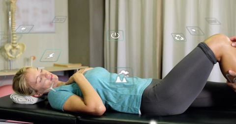 Woman undergoing knee assessment on treatment table in physiotherapy clinic with therapist