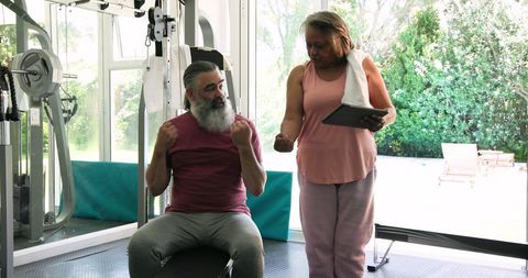 Senior couple exercising in home gym with technology