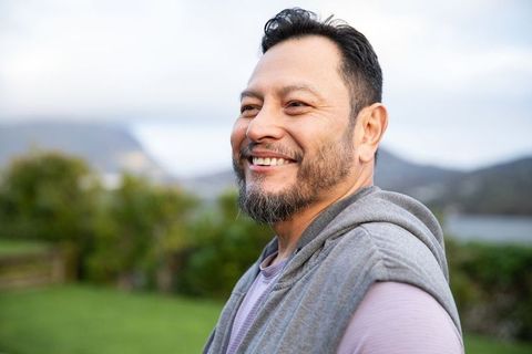 Smiling mature asian man looking away lakeside portrait relaxing outdoors