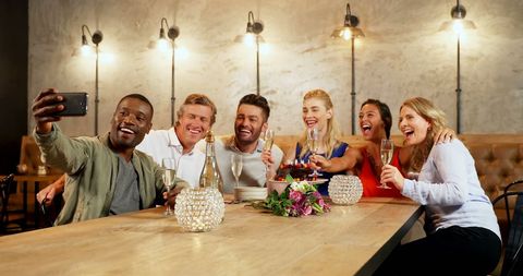 Diverse Group Enjoying Celebration in Restaurant Taking Selfie