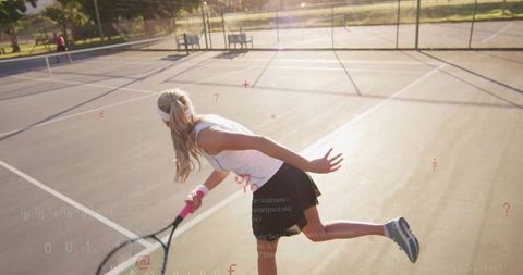 Determined Female Tennis Player Swinging Racket on Sunlit Court