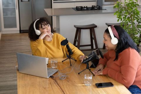 African american women recording home podcast at kitchen table with mics and headphones