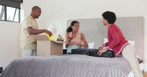 Family joyfully packing suitcase for vacation journey at home