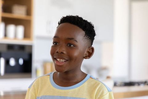 Smiling african american boy wearing pastel tee in bright modern kitchen