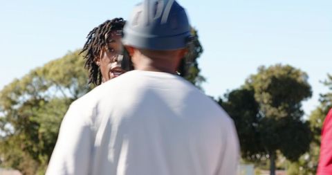 Helmeted coach directing while african american runner jogging and stretching outdoors