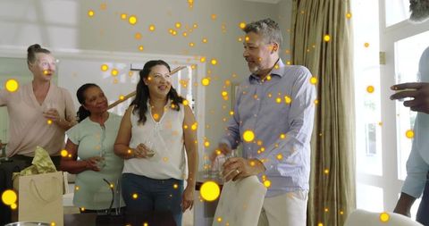 Multigenerational friends celebrating with drinks at sunlit home party with bokeh lights