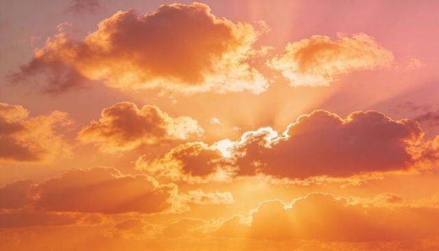 Glowing golden sunset cloudscape casting radiant sunbeams through layered cumulus