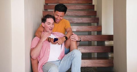 Joyful Same-Sex Couple Laughing and Relaxing on Staircase at Home
