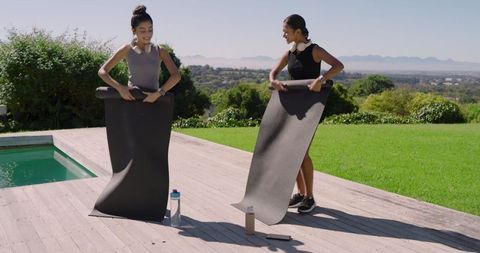 Women Preparing for Outdoor Yoga Near Scenic Infinity Pool