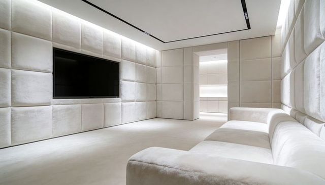 Luxury minimalist home theater featuring quilted cream walls and plush sectional sofa