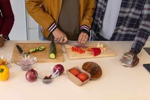 Group chopping fresh vegetables on kitchen counter for casual home cooking and meal prep