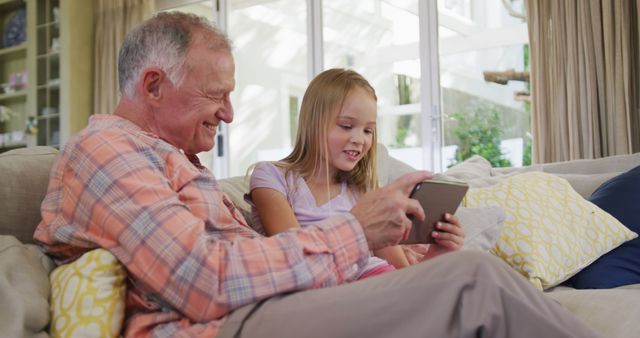 Grandfather and Granddaughter Laughing and Bonding on Couch with Tablet - Download Free Stock Images Pikwizard.com