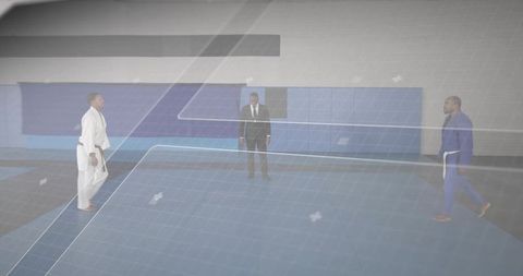 Officiating judo match with referee in suit and competitors wearing white and blue gi on training ma