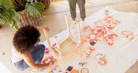 Creative duo painting a wooden chair for a home diy project