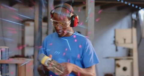 Inspecting angle grinder in workshop wearing safety goggles and hearing protection