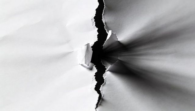 Jagged Vertical Tear in White Paper Revealing Narrow Dark Gap and Dramatic Shadows