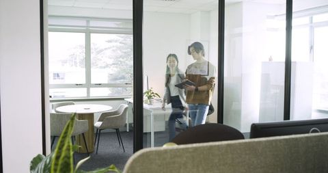 Professionals Collaborating Inside Modern Glass-Walled Office