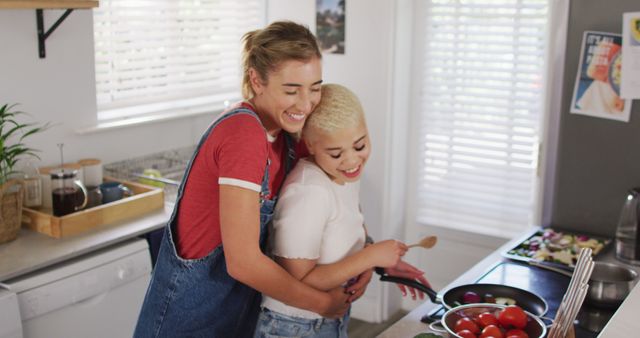 Happy diverse female couple cooking vegetables and embracing in kitchen - Download Free Stock Photos Pikwizard.com