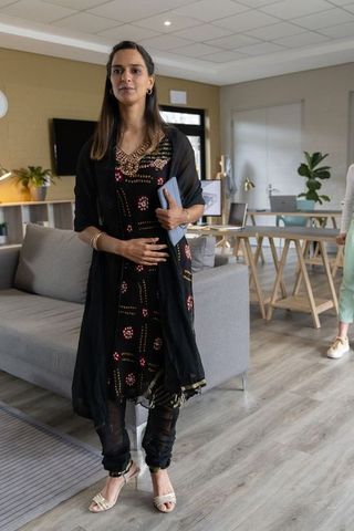 Indian professional woman holding tablet in modern open office lounge coworking collaboration