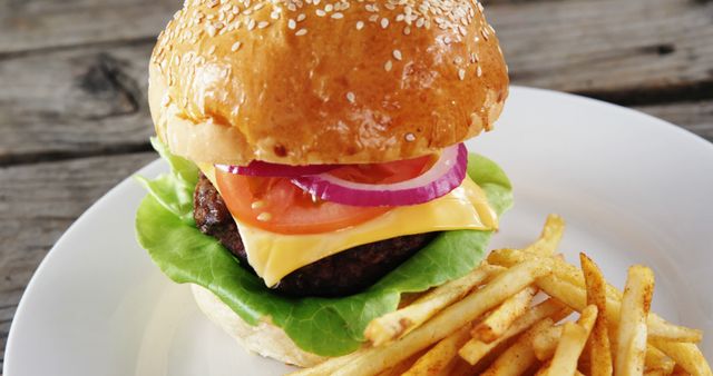 A classic cheeseburger with lettuce, tomato, and onion is served alongside a portion of fries on a white plate. Perfect for a casual dining experience, this meal is a popular choice in American cuisine.