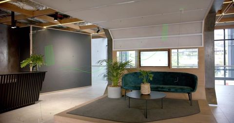 Curved teal velvet sofa on raised platform in modern industrial lobby with round coffee table