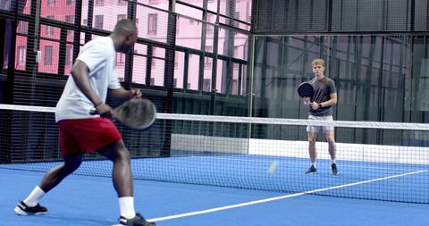 Two Men Playing Competitive Padel on Blue Outdoor Court
