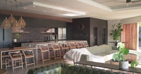 Modern open-plan kitchen island with light stone countertop, rattan pendants and wooden bar stools