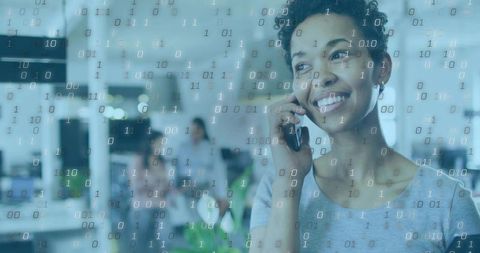 Smiling professional talking on smartphone in modern open office with binary data overlay