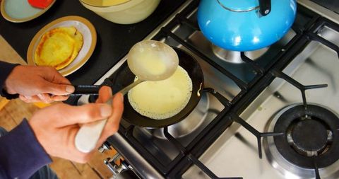 Man Preparing Pancakes in Home Kitchen on Stove