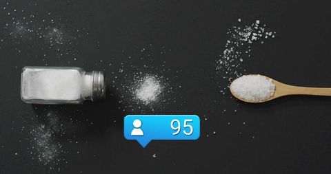 Minimalist flatlay spilling salt from glass shaker beside wooden spoon with 95 badge