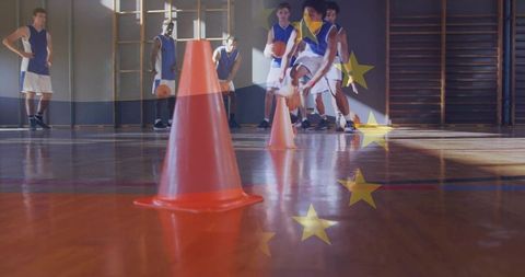 Youth basketball team practicing cone dribbling drill on sunlit school gym hardwood court